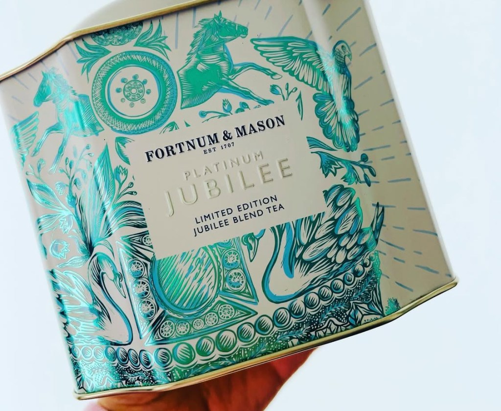 Una lattina di tè in edizione limitata 'Platinum Jubilee' di Fortnum & Mason, con un design elegante e decorazioni floreali e animali.