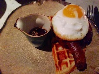 Piatto di Duck and Waffle con coscia d'anatra croccante e uovo fritto su un waffle, servito con sciroppo d'acero.