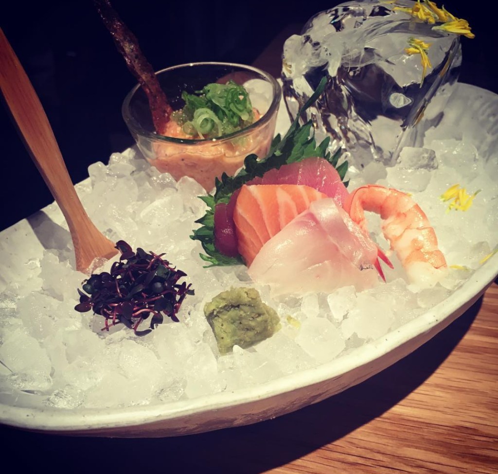 Piatto di sushi fresco servito su ghiaccio tritato, con diverse varietà di pesce crudo, wasabi e guarnizioni, presentato in modo elegante. Ristorante Roka a Londra