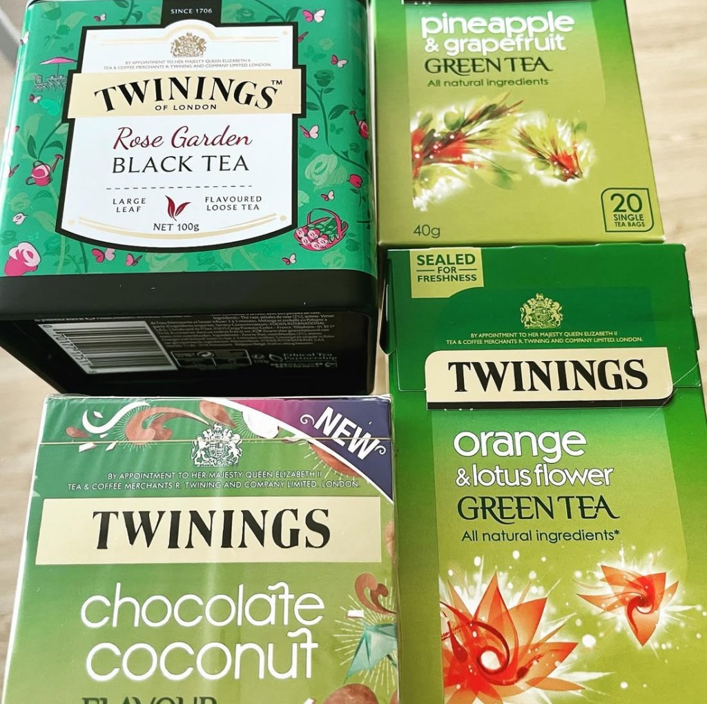 Scatole di tè Twinings assortite, inclusi tè neri e verdi con vari gusti come rose, ananas, cocco e fiori di loto.