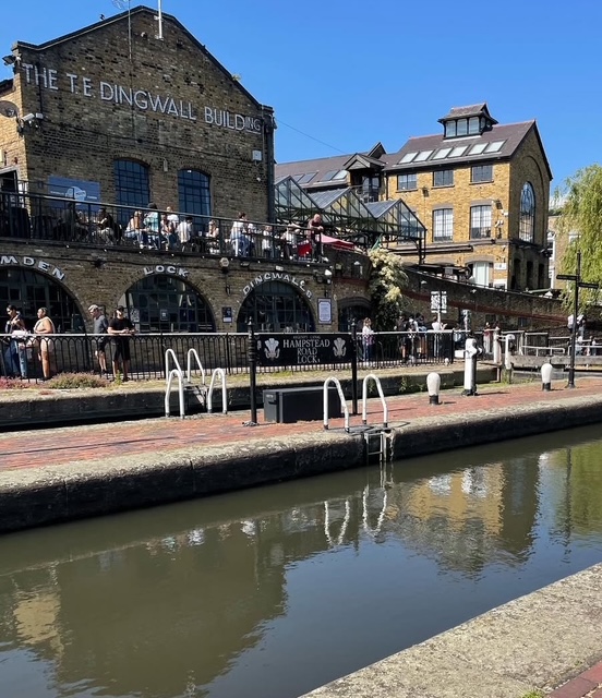 Vista del canale con il T.E. Dingwall Building e riva affollata, in una giornata di sole a Londra.