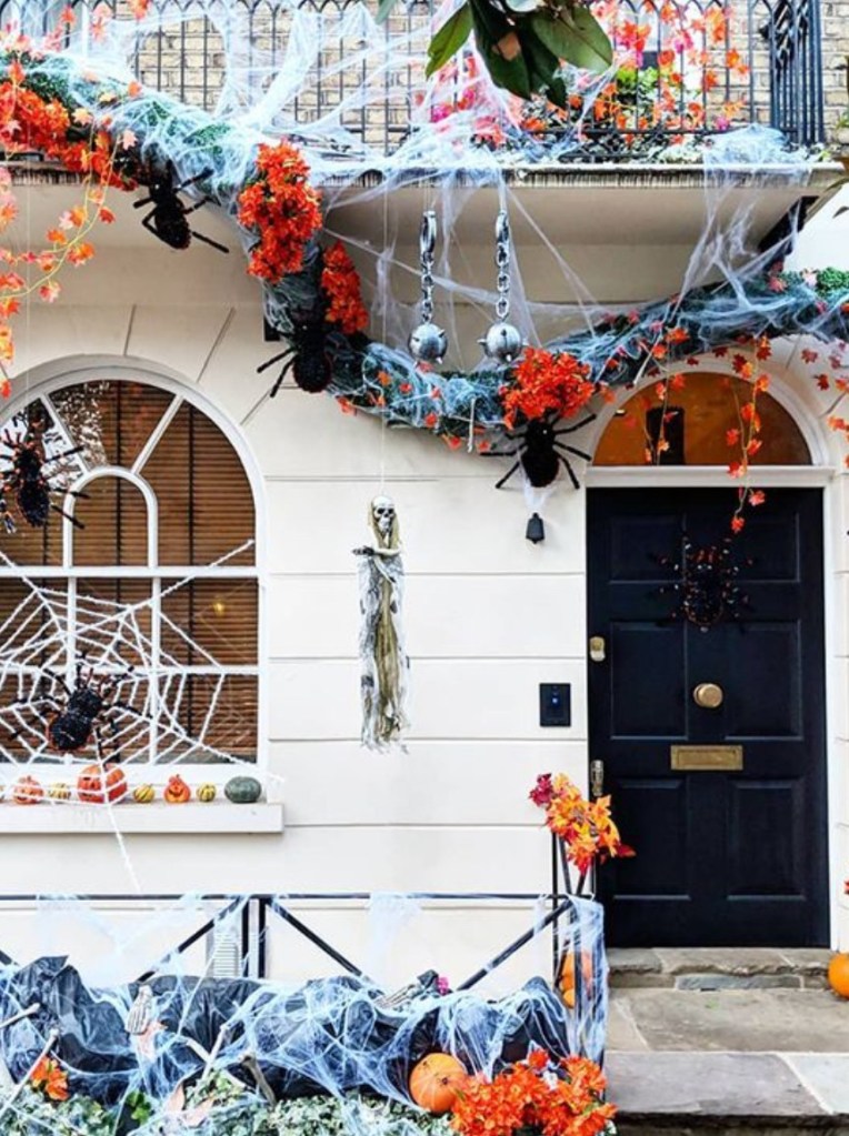 Facciata di una casa di Londra decorata per Halloween con ragnatele, zucche, finti ragni e foglie autunnali.