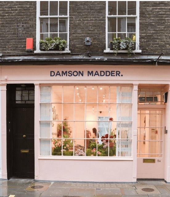 Negozio Damson Madder, con facciata rosa e ampie finestre che mostrano decorazioni floreali all'interno.