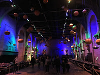 Interno di una location negli Harry Potter Studios di Londra decorata per Halloween, con luci blu e zucche sospese, mentre persone passeggiano nel corridoio.