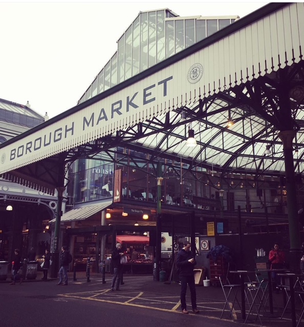 Entrata del Borough Market a Londra, con diverse persone che passeggiano e l'iconico tetto in metallo e vetro.