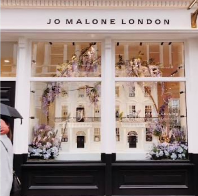 Vetrina del negozio Jo Malone a Londra, decorata con fiori e dettagli eleganti.