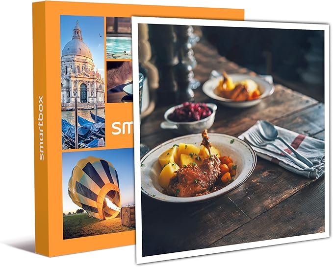 Imballaggio di una Smartbox con immagini di esperienze, accanto a un piatto di cibo caldo servito su un tavolo di legno.