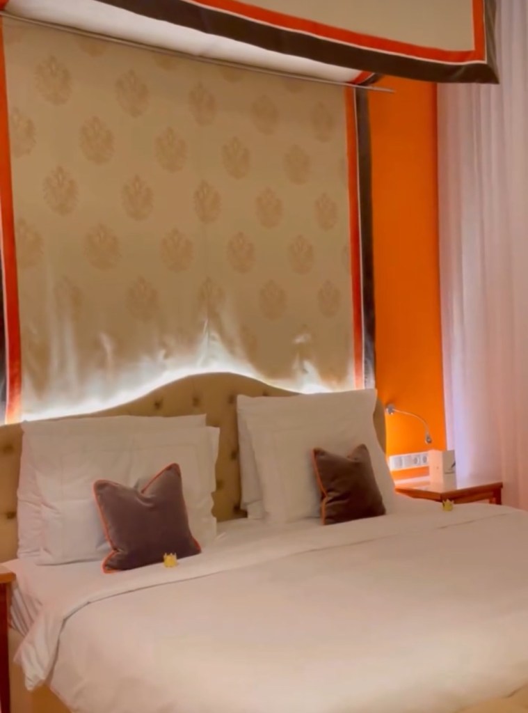 Camera elegante del Kaisehof hotel di Vienna con letto matrimoniale, cuscini decorativi e una grande finestra che fa filtrare la luce.