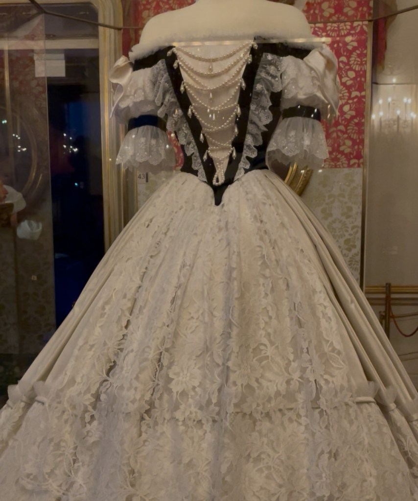 Abito storico dell'imperatrice Sissi, esposto al museo a lei dedicato a Vienna, con dettagli in pizzo bianco e perle, rappresentativo della moda del periodo imperiale a Vienna.