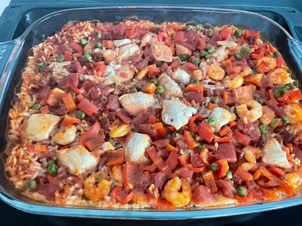 Piatto di riso al forno con gamberi, pollo, pomodori e peperoni.
